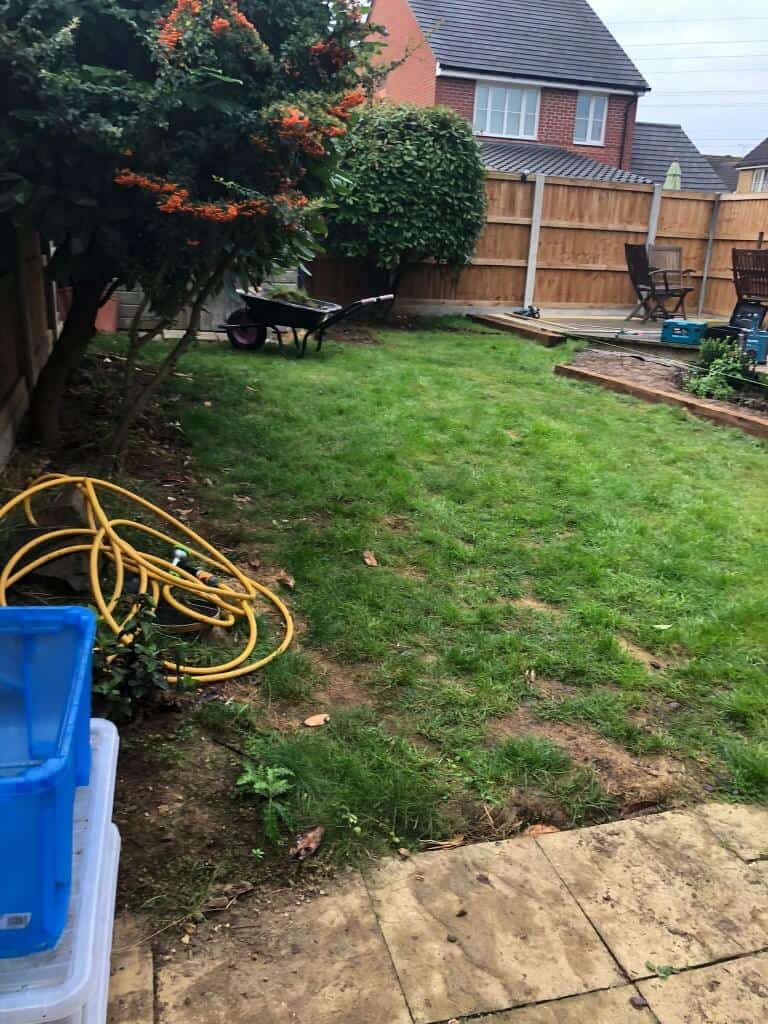 Backyard garden with new wooden fence and lawn area.