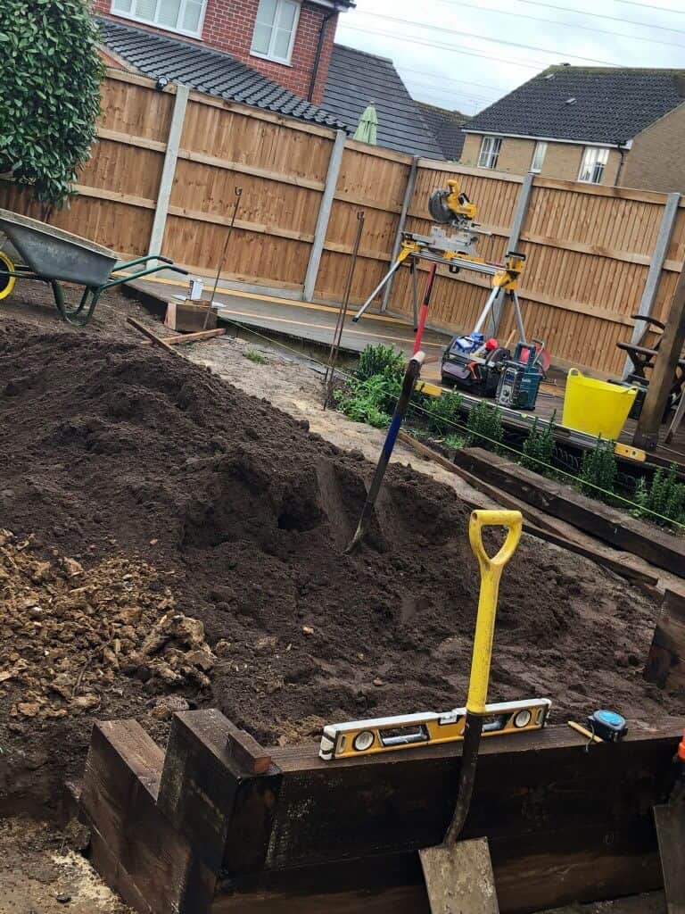 Garden fencing and landscaping work in progress with tools and soil.