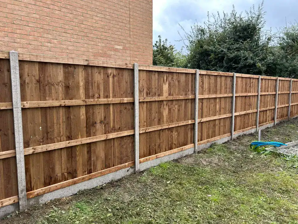 Wooden garden fence with vertical panels and concrete posts.