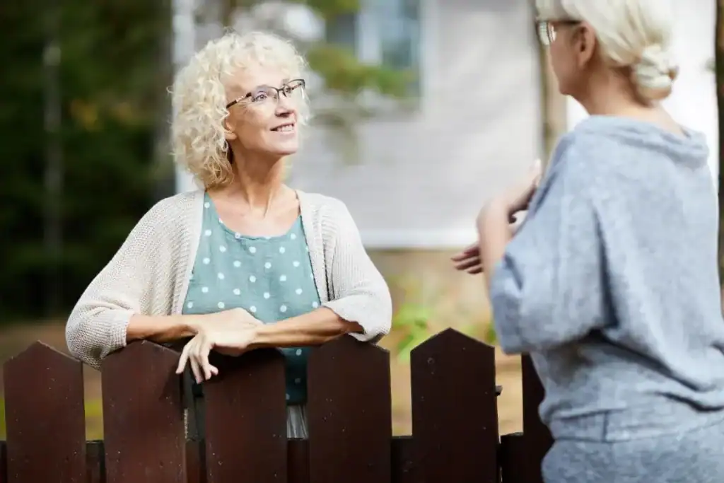 Older woman talking to a younger woman in a garden setting.