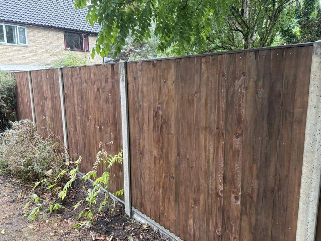 Close-up of a newly installed wooden garden fence with greenery nearby.