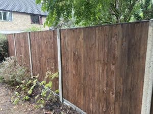 Close-up of a newly installed wooden garden fence with greenery nearby.