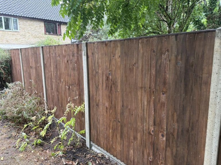 Close-up of a newly installed wooden garden fence with greenery nearby.