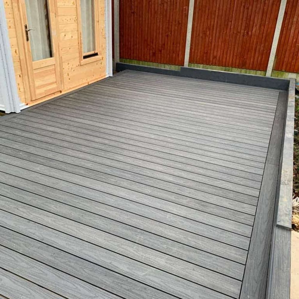 Long-lasting composite decking with wooden fencing in a garden.