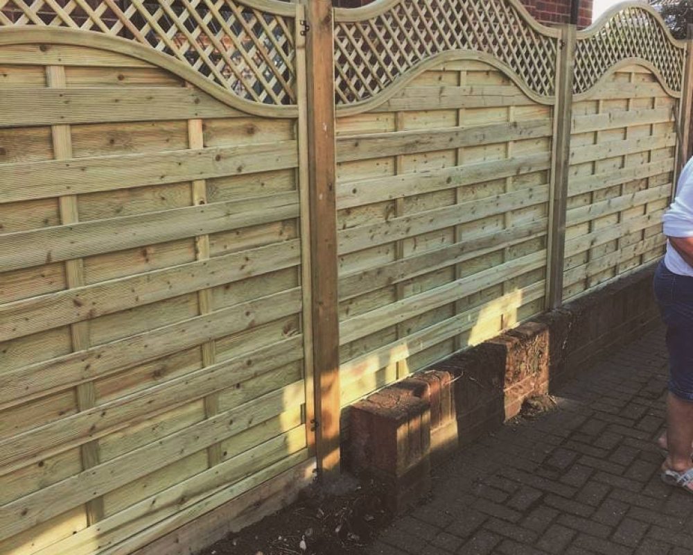 New wooden garden fence with decorative top design for privacy and style.