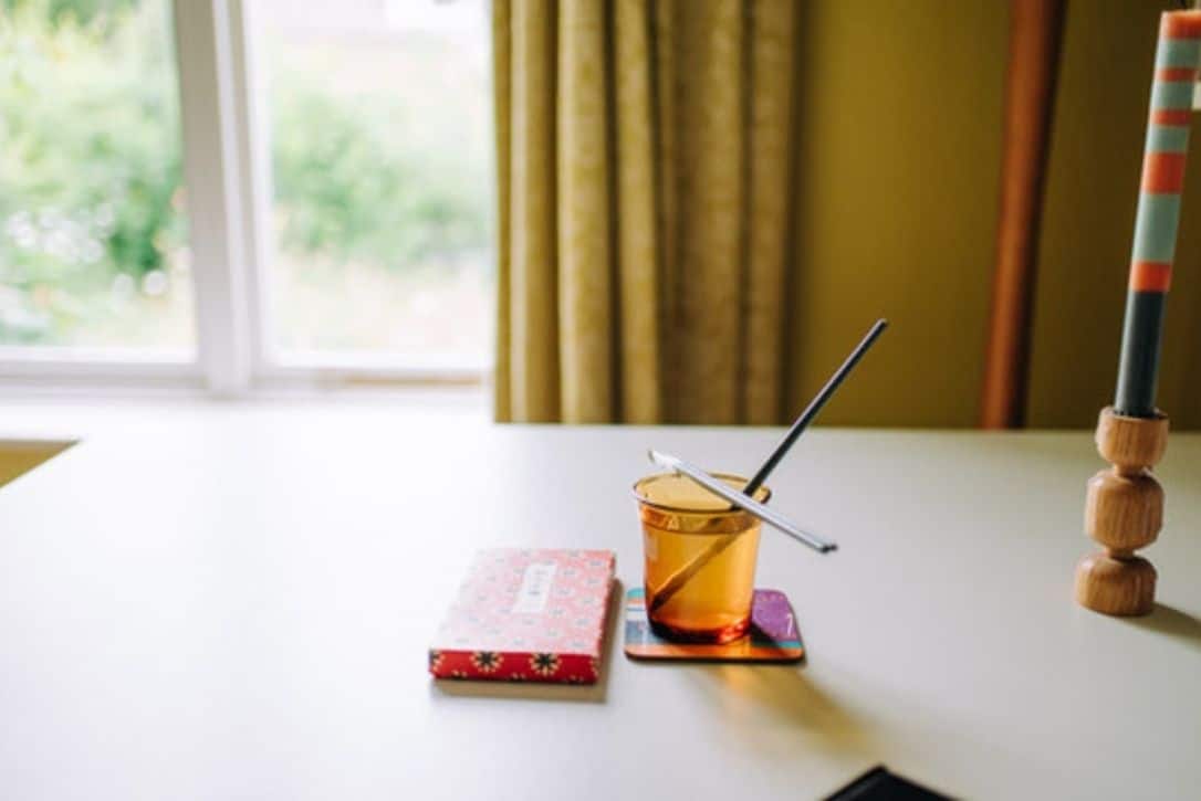 Photo of a glass of water an watercolours on a peaceful desk.