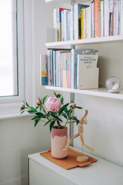Photograph of bookshelf with pink peonies