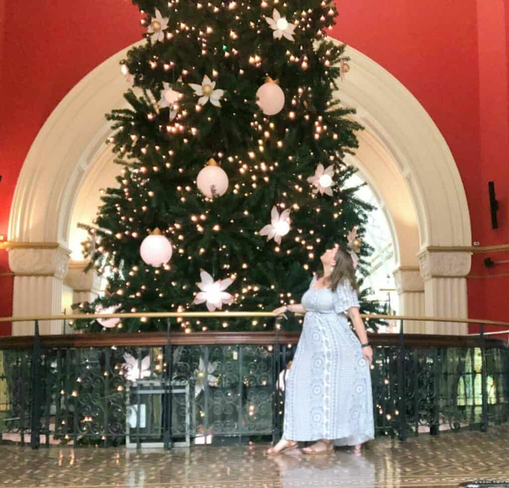 Emma is standing side on looking up at a giant Christmas Tree