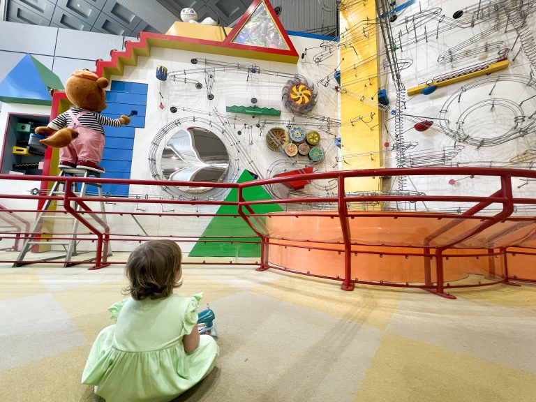 This image showcases a lively indoor play space in Osaka designed for children, including toddlers and babies. It features bright, engaging equipment, a friendly mascot, and a safe environment for kids to enjoy active play and exploration.