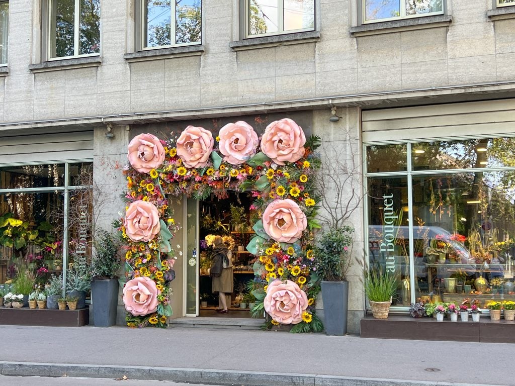 Beautiful flower shop entrance decorated with large pink roses and vibrant sunflowers, creating an inviting and picturesque scene in Basel.