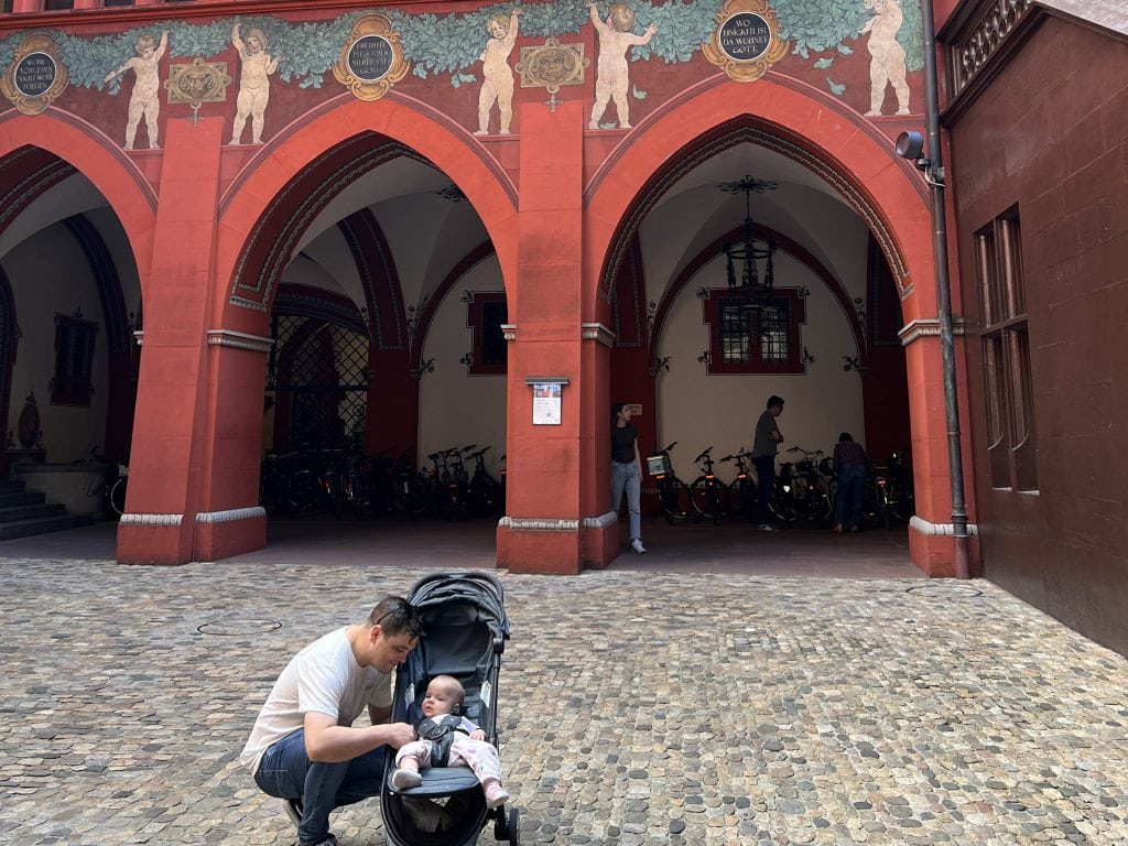 Family enjoying a day in Basel's historic old town with a stroller and children.