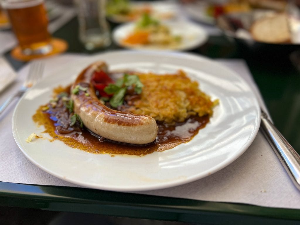 Delicious Swiss sausage served with rich gravy and crispy rösti, perfect for a family meal during a day trip exploring Basel with kids from Zurich.