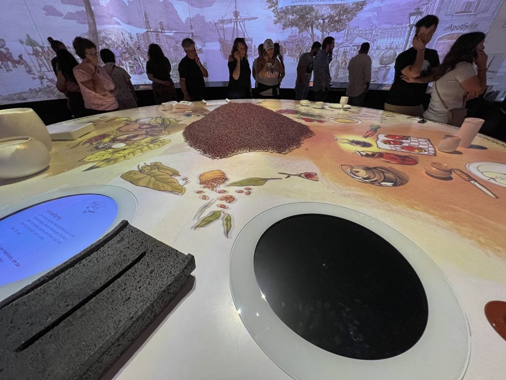 Visitors exploring the interactive Lindt chocolate tasting table at the Lindt Home of Chocolate, with a focus on the immersive chocolate journey for families.