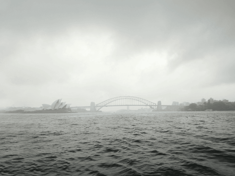 Rainy day Sydney Harbour with iconic landmarks, cloudy skies, and choppy waters, perfect for exploring rainy day activities in Sydney.
