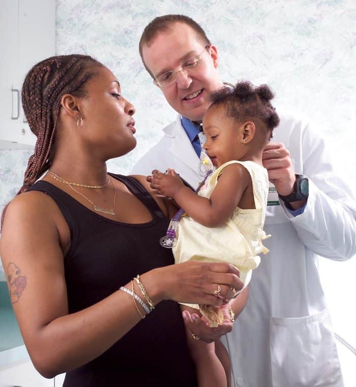 Mother holding baby with doctor