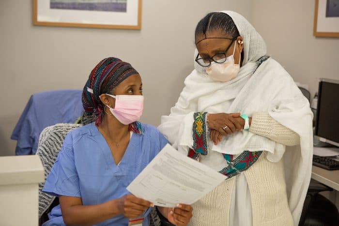 A health care provider shows a woman with a head covering a file