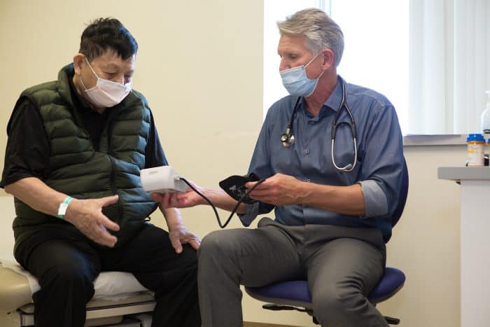 A clinician helps take a man's blood pressure