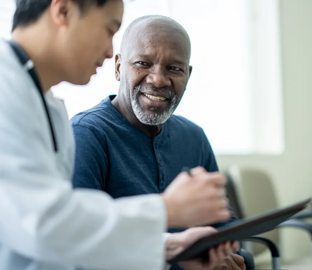 Photo of doctor and older man discussing clinical trials
