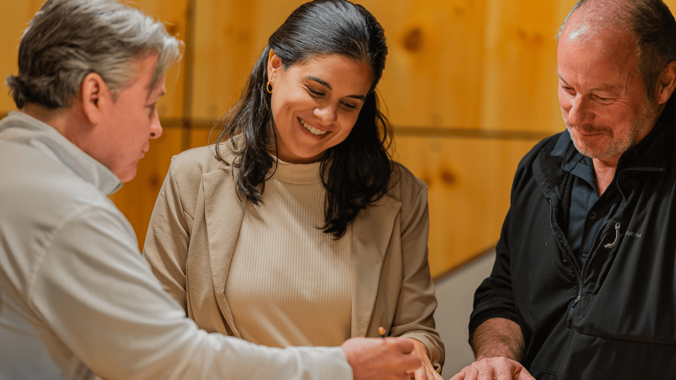 A business owner smiling while meeting with two business consultants during a confidential coaching session.