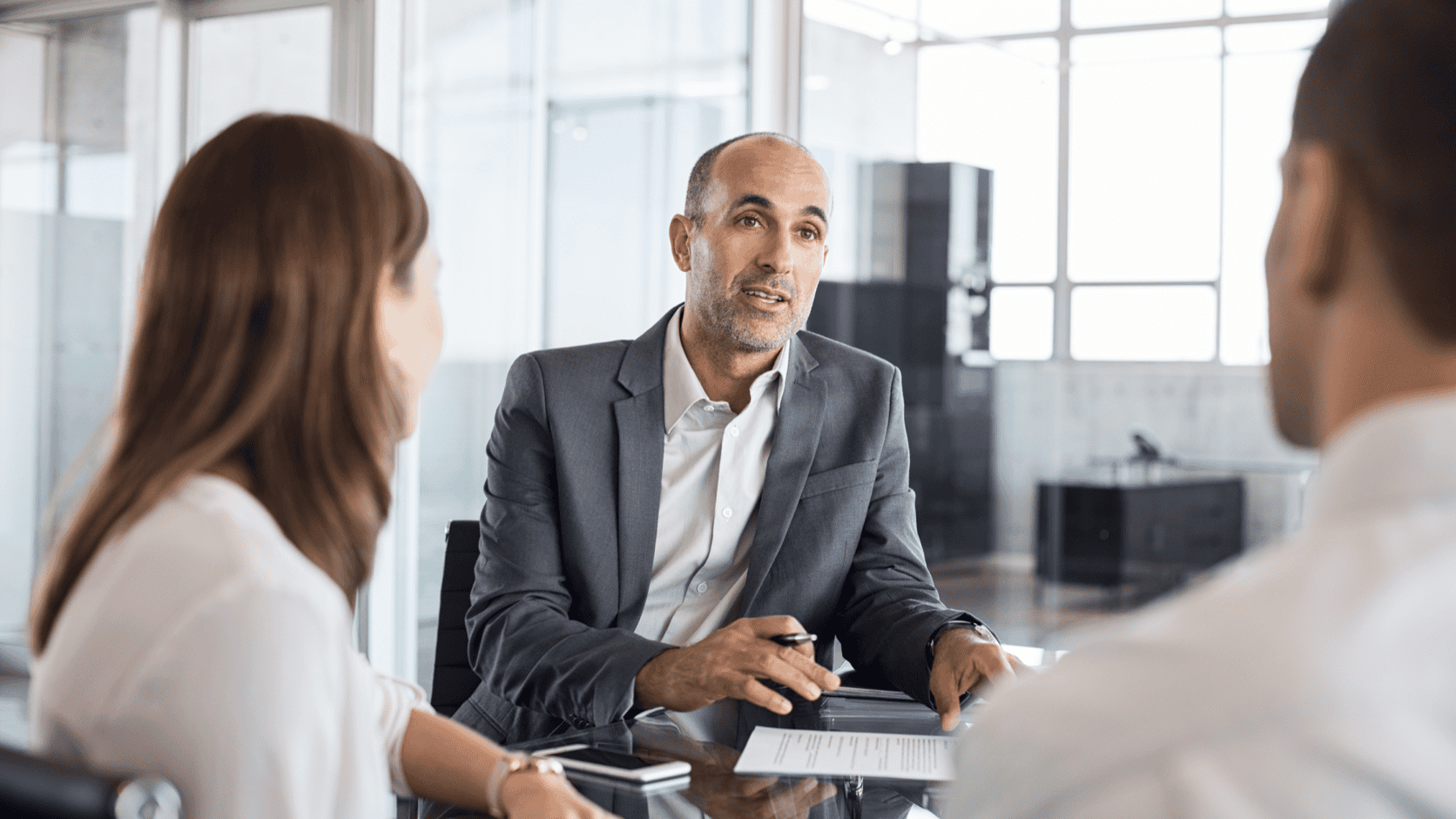 M&A advisor meeting with business owners at a conference table to discuss selling their business