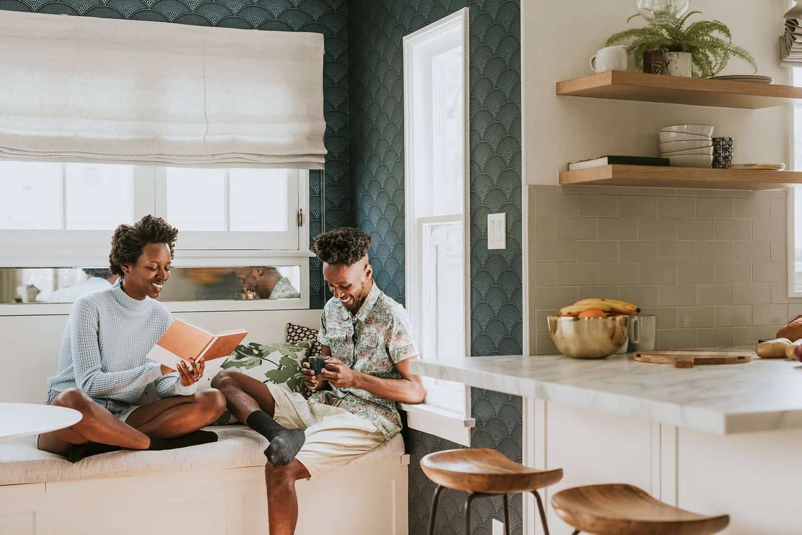 Contemporary kitchen with two friends relaxing and reading in a stylish, well-lit space.