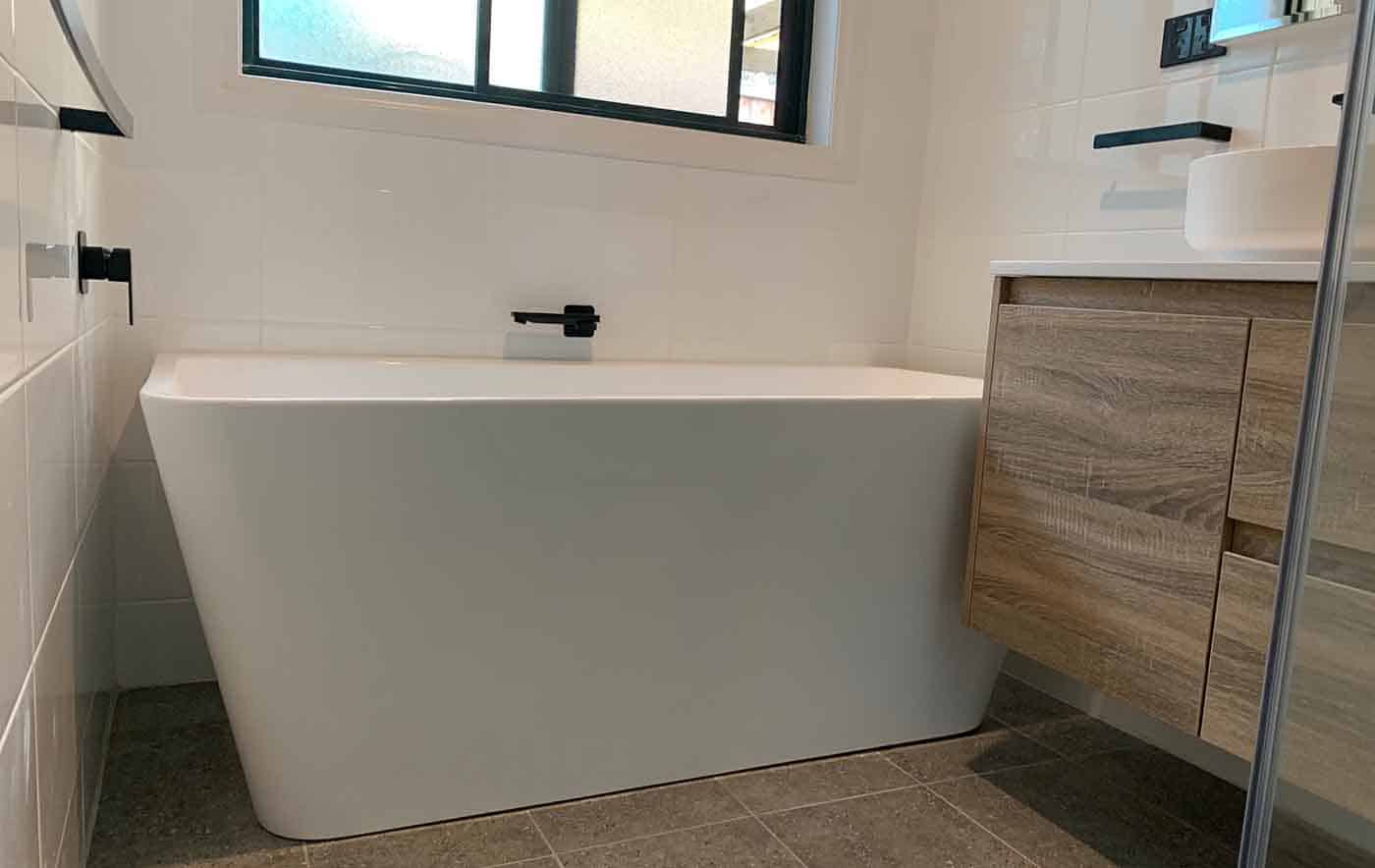 Elegant white freestanding bathtub with sleek design in a contemporary bathroom setting.