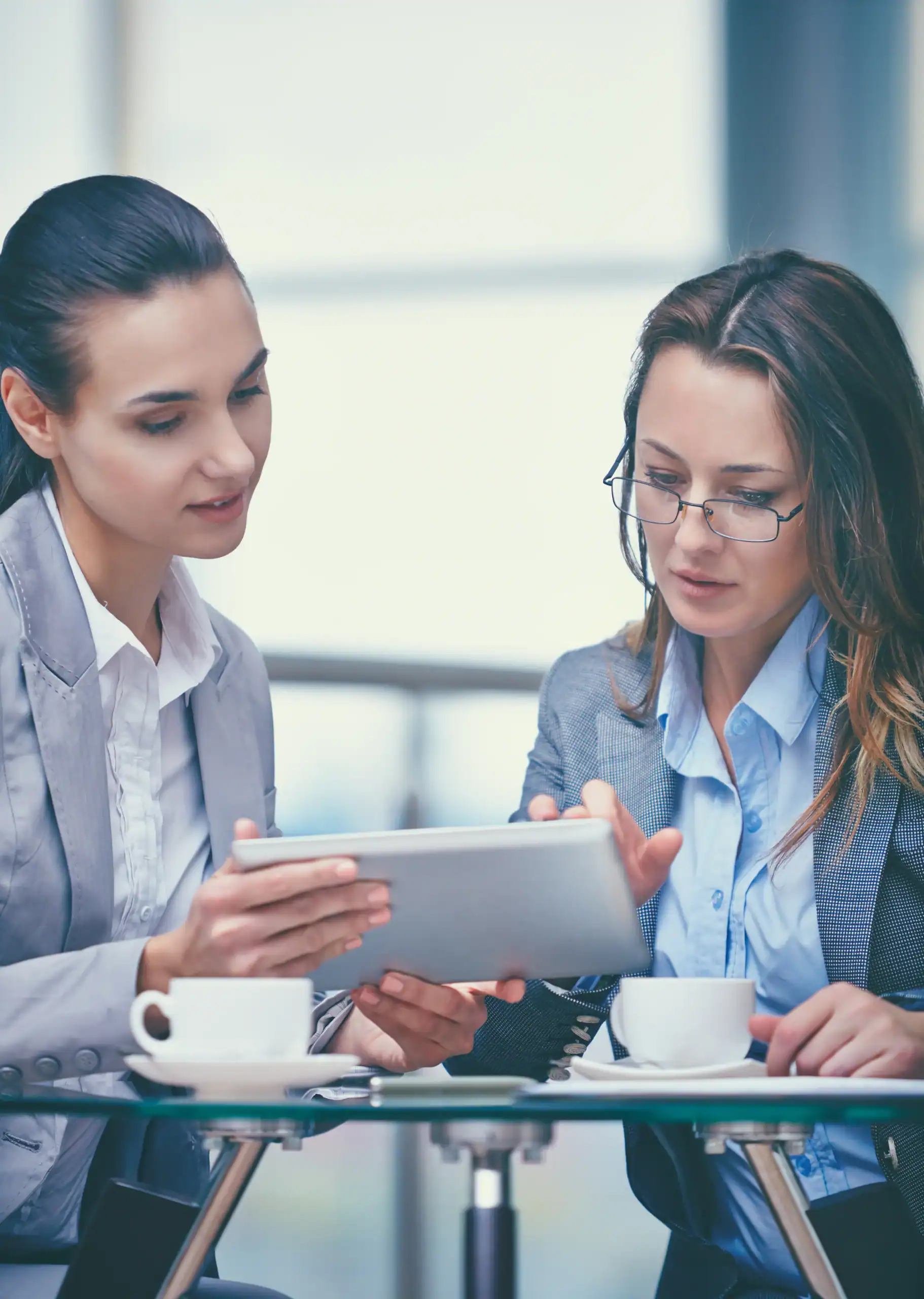 Two business professionals reviewing customer experience insights together on a tablet over coffee, representing the manager coaching, accountability, and collaborative action planning that Feedback ASAP enables to drive frontline performance improvement.
