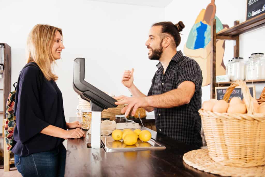 A staff member and a returning customer in conversation, representing a customer retention strategy built on frontline service