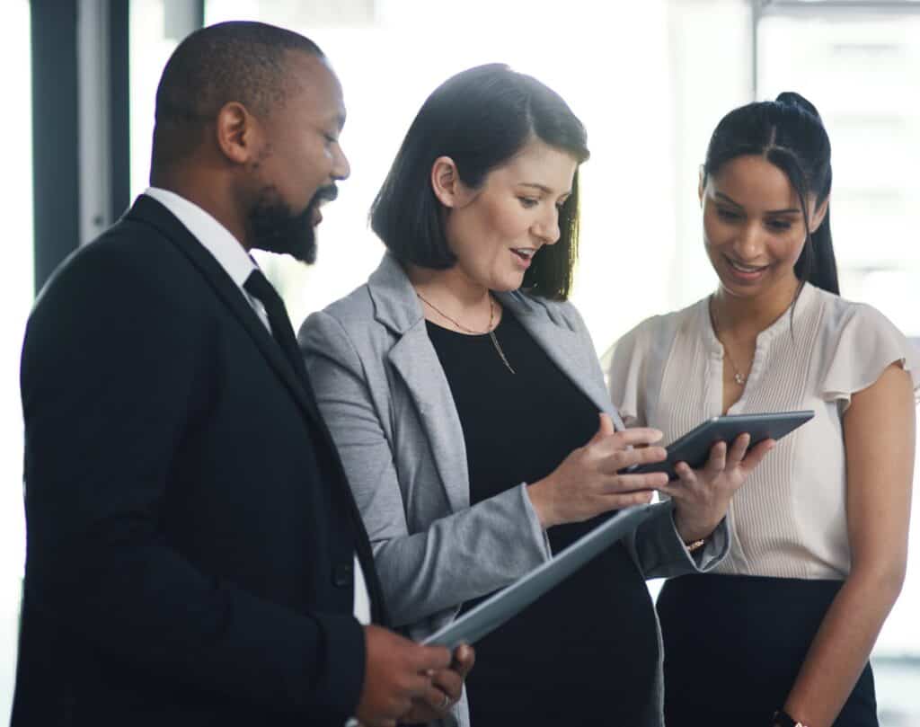 AI in CX growth programs: three colleagues reviewing AI-flagged customer feedback data together on a tablet