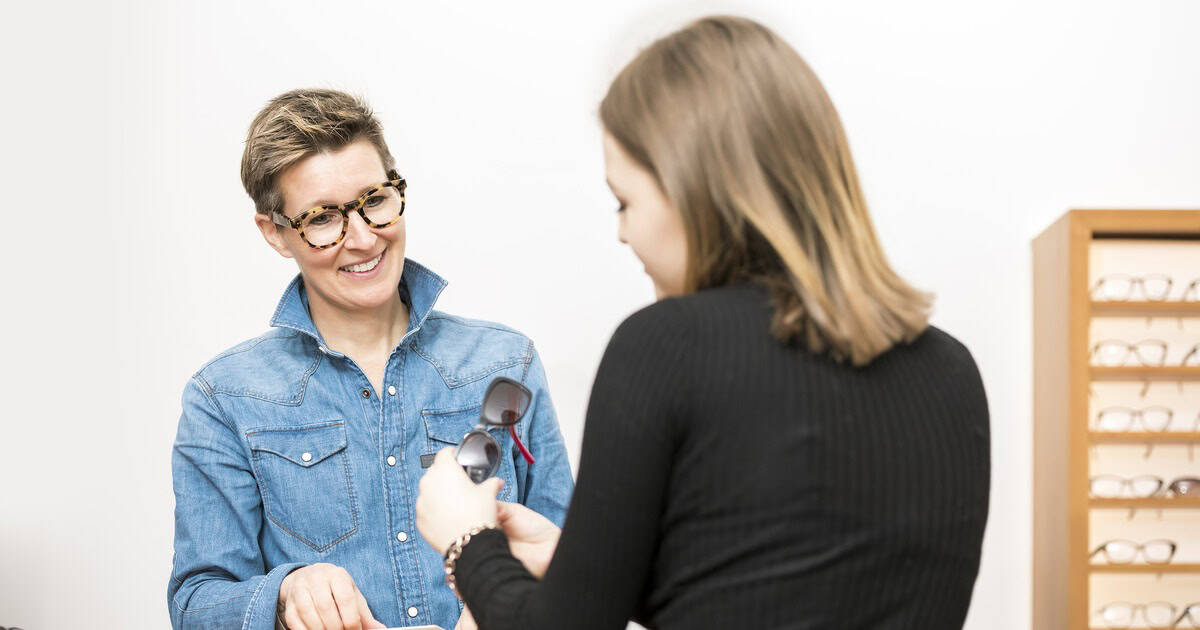 Optician and customer choosing glasses together in a bright optical store