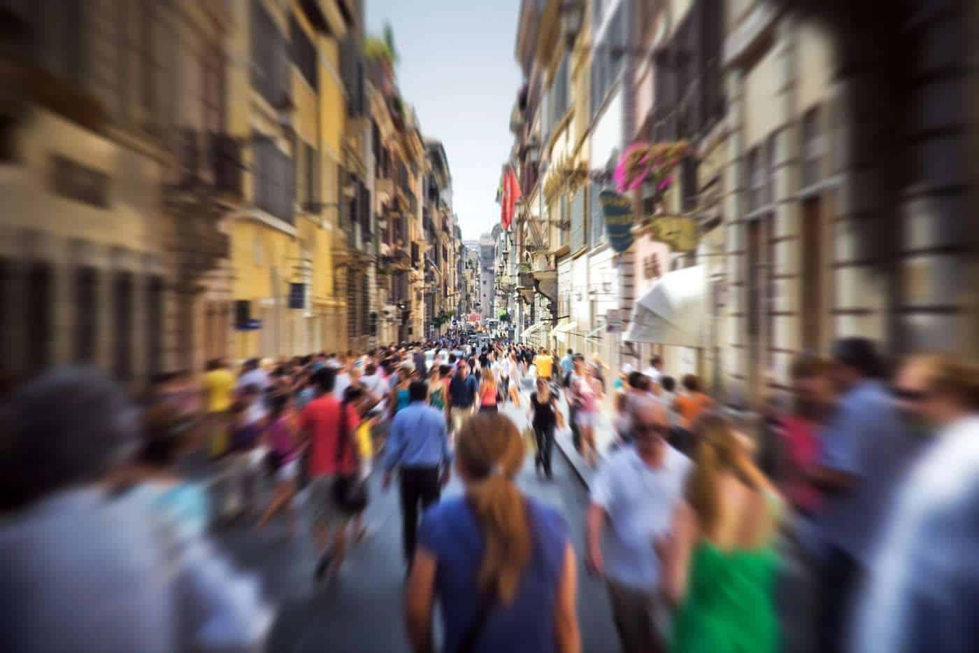 Gente caminando por una calle urbana concurrida con edificios históricos a los lados.