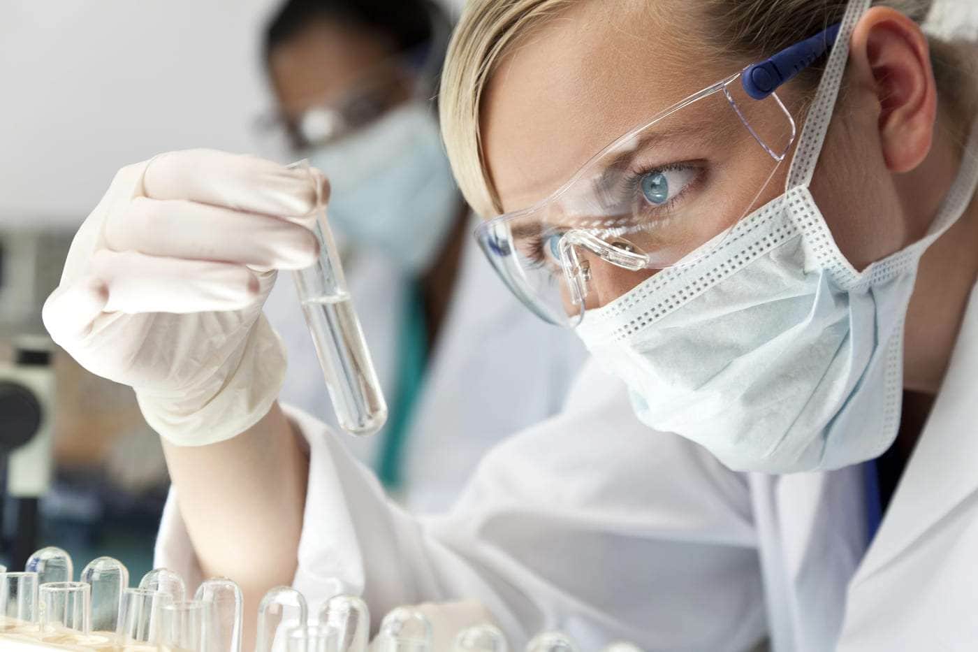 Análisis científico en laboratorio con investigadora usando protección facial y guantes.