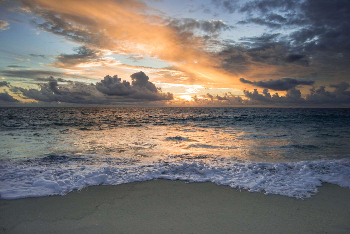 Bellas vistas del atardecer en la playa con nubes y olas suaves en el mar.