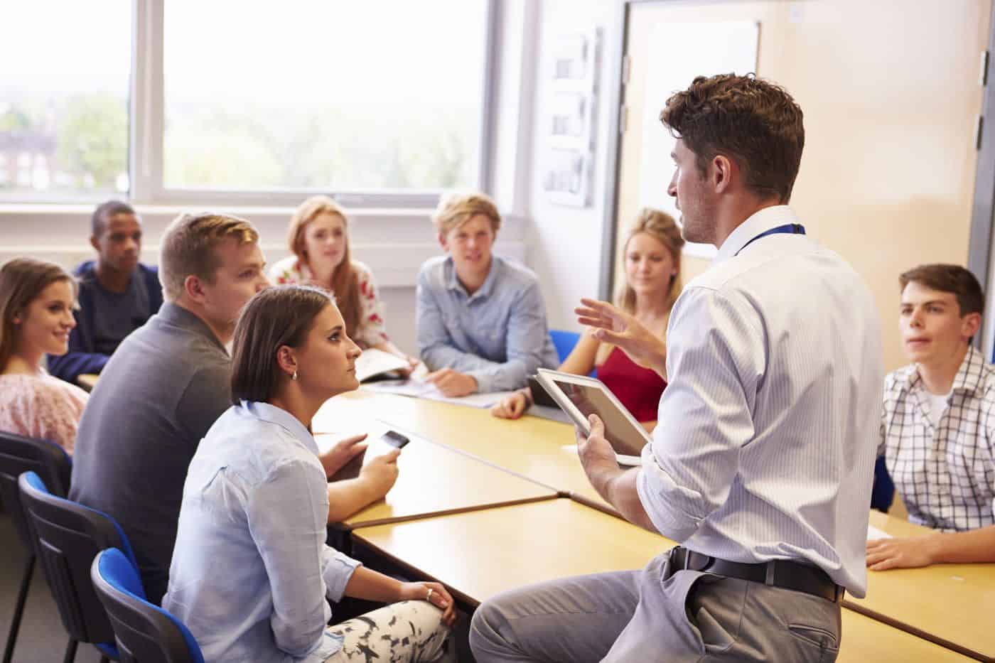 Pensador dando una charla en un aula universitaria con estudiantes atentos.