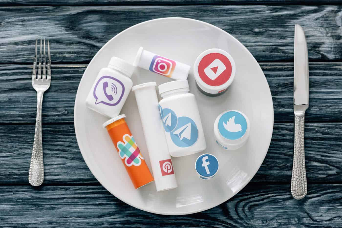 Alt: Pirámide de pastillas con logotipos de redes sociales sobre plato blanco y fondo de madera.