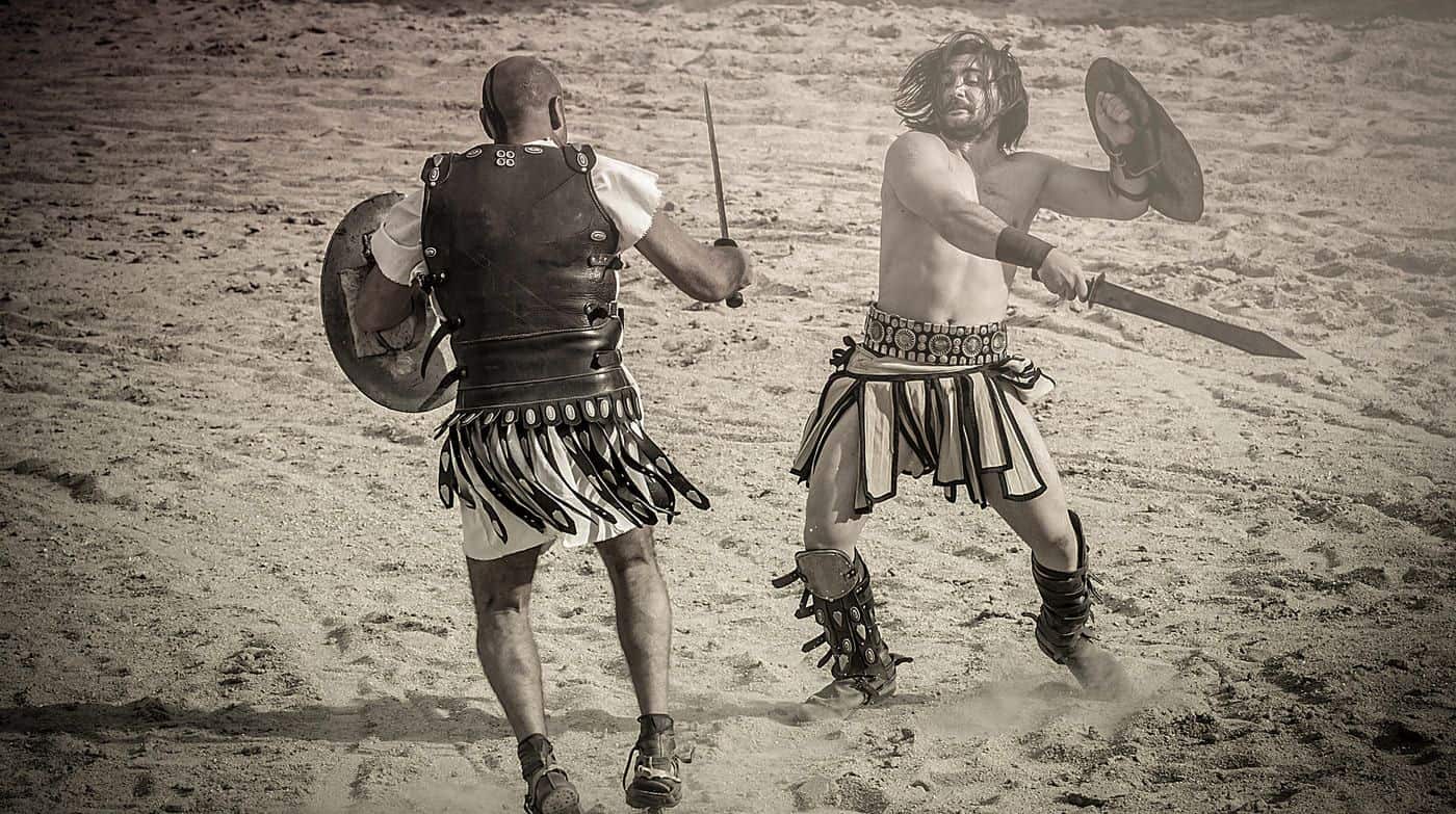 Guerreros romanos luchando con espadas y escudos en un combate histórico en la arena.