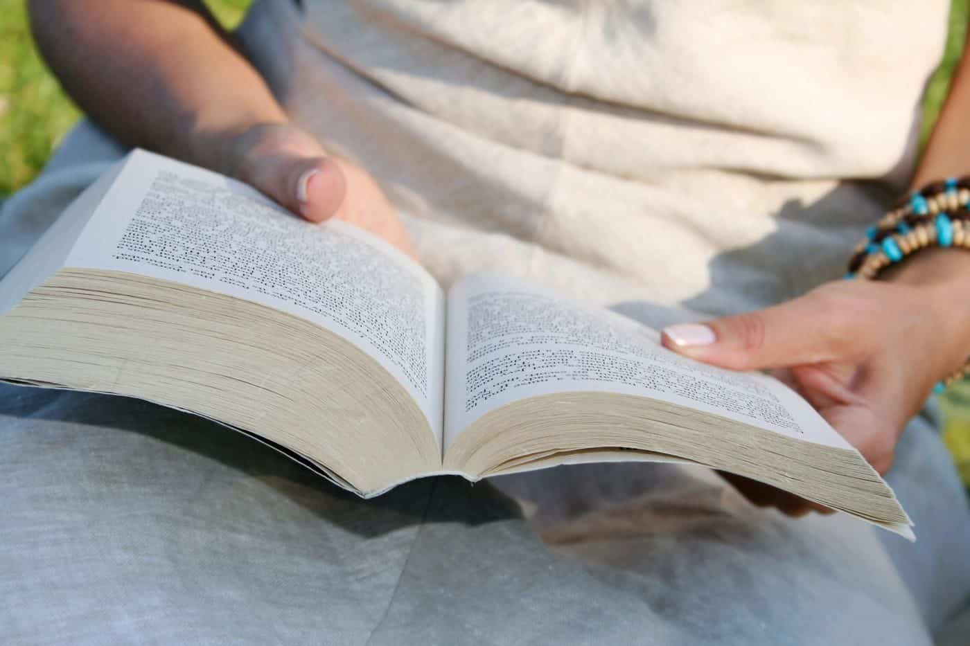 Filósofo leyendo un libro al aire libre, reflexionando sobre conceptos filosóficos en un entorno natural.