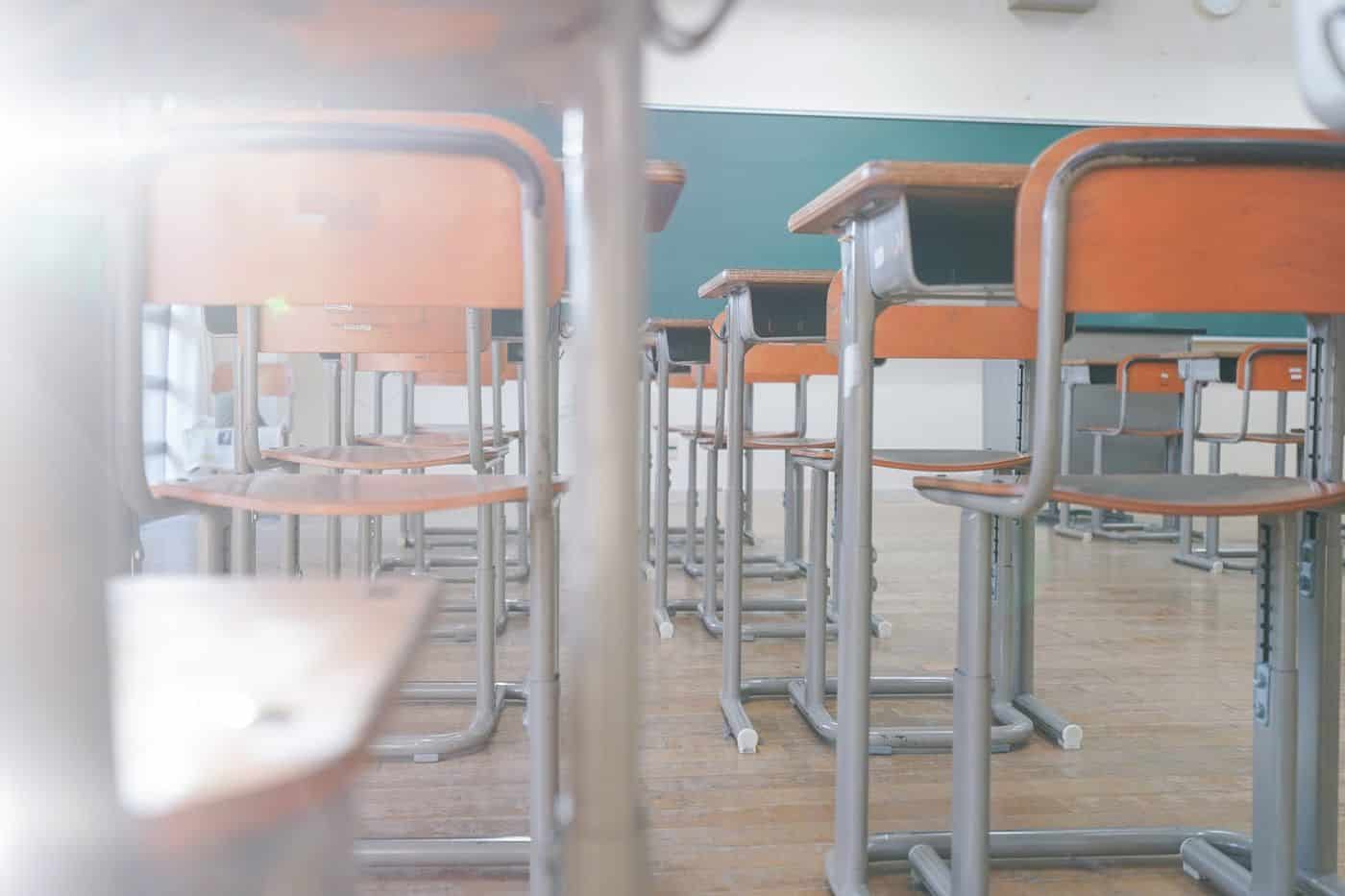 Filas de pupitres en un aula escolar vacía.