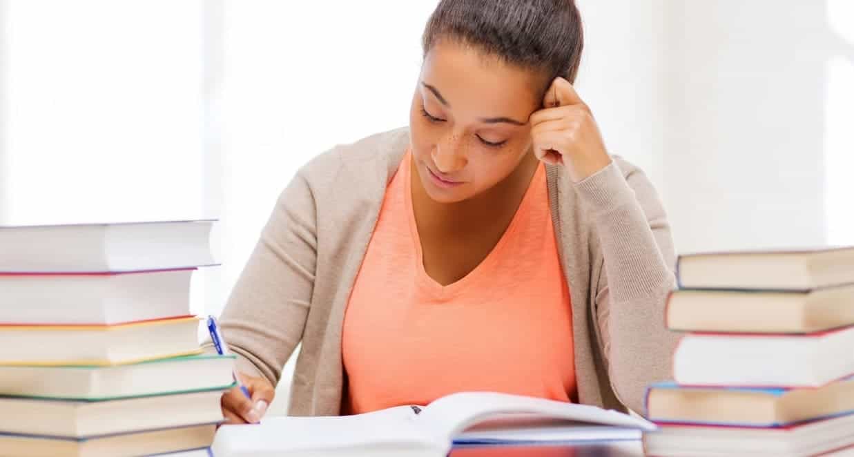Estudia con enfoque, rodeada de libros en un ambiente de estudio tranquilo, buscando profundizar en filosofía y conocimiento.