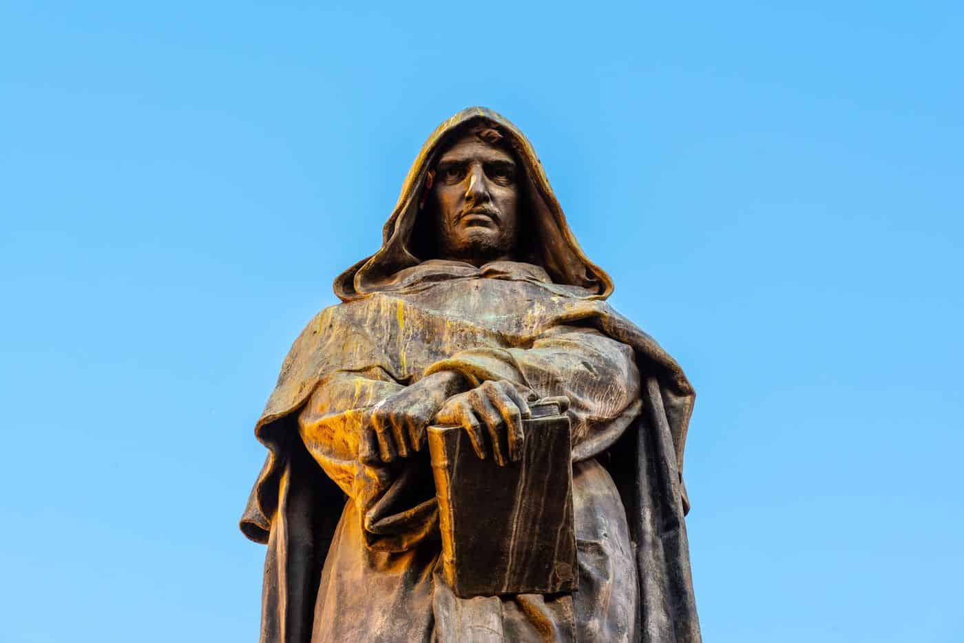 Filósofo en escultura con libro y pluma, símbolo de sabiduría y reflexión filosófica en la plataforma del saber.