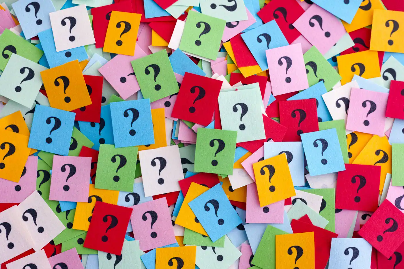 Preguntas en notas de colores con signos de interrogación, fondo de papeles de colores.
