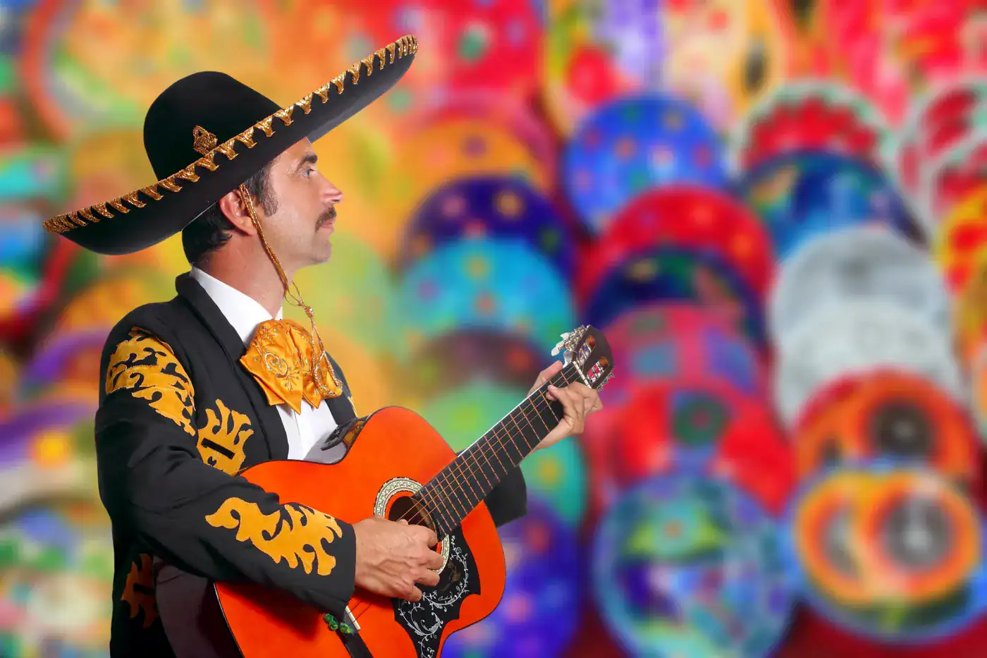 Sombrero mexicano tradicional y guitarra en fondo colorido y artístico.