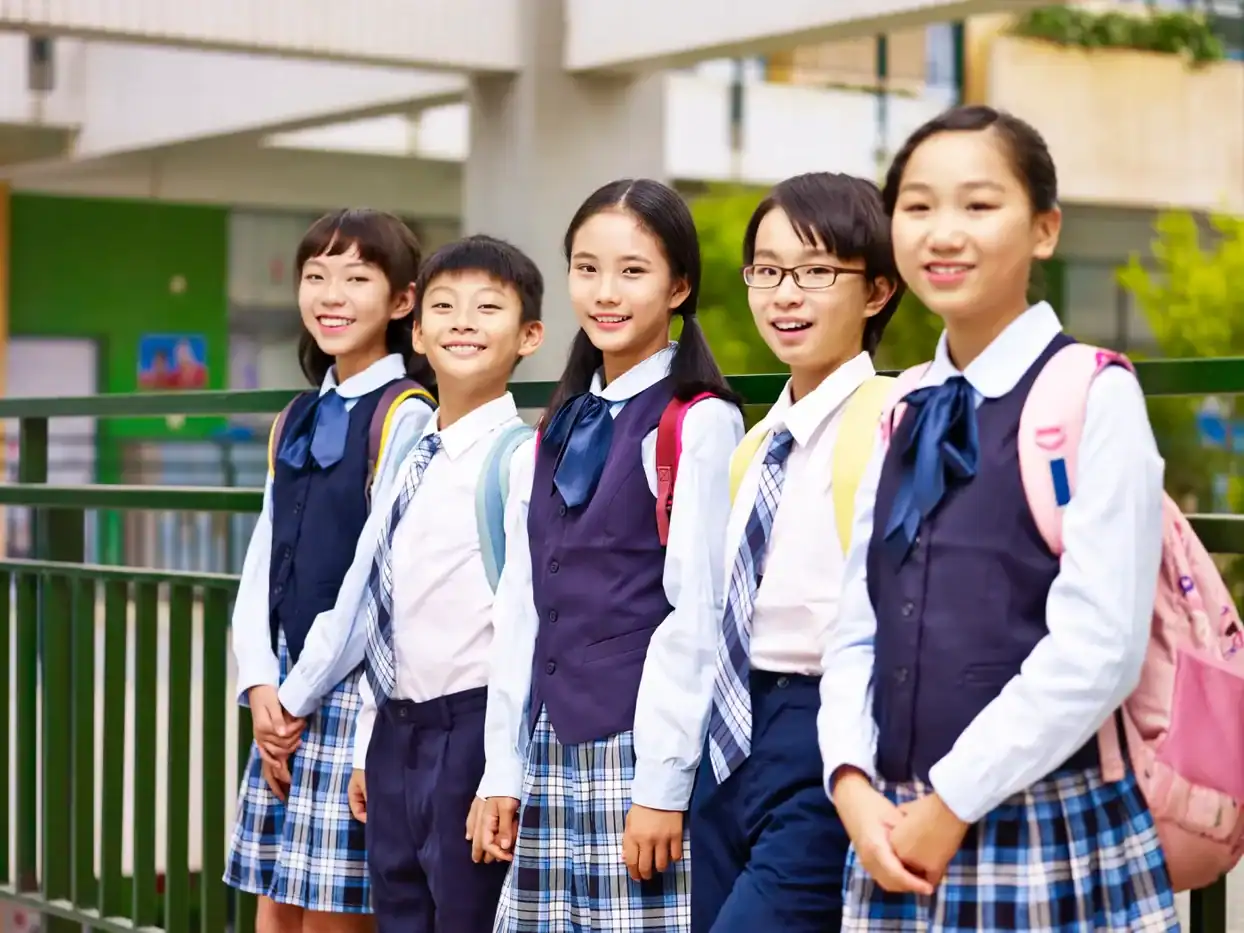 Estudiantes de escuela primaria con uniformes escolares en fila al aire libre.