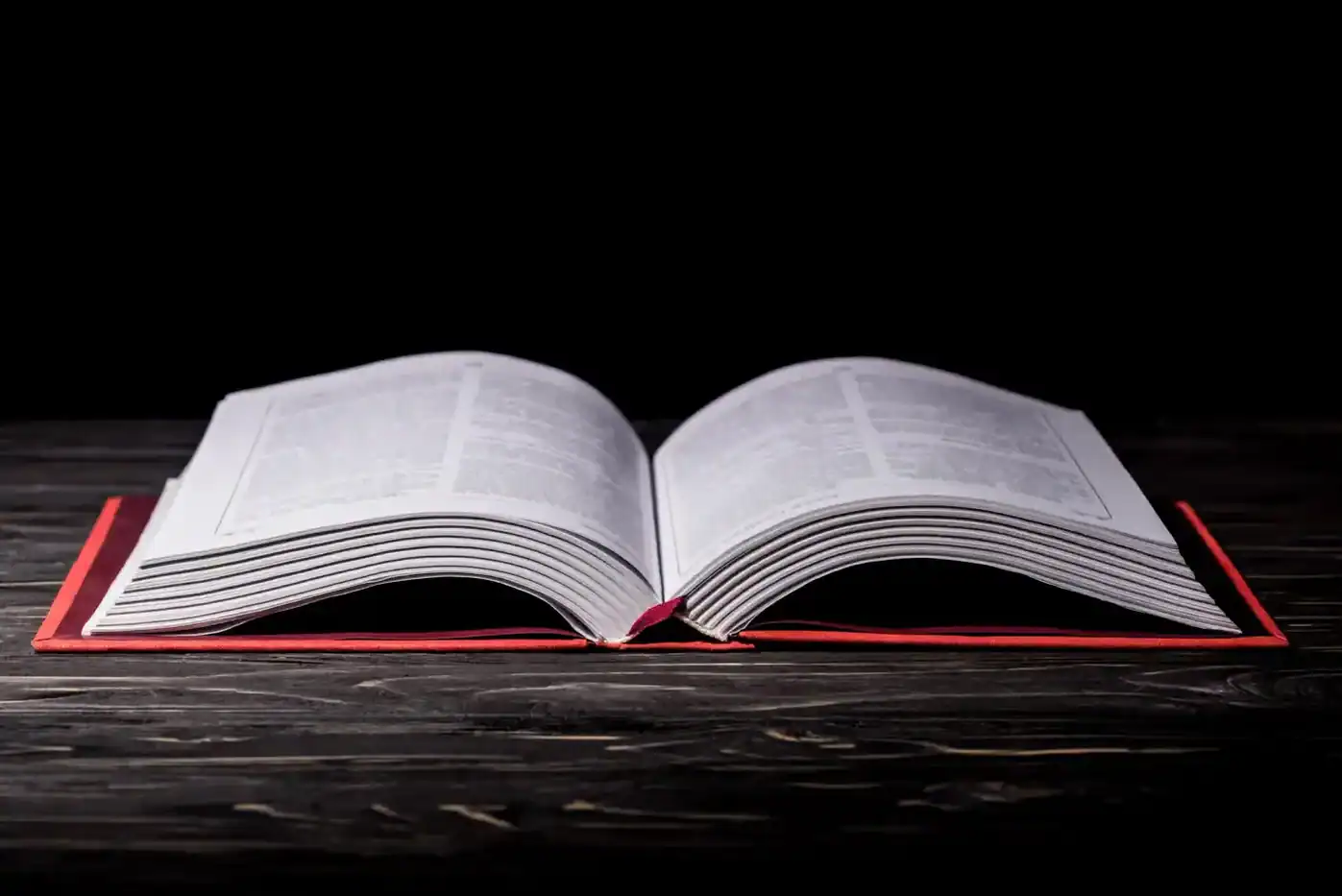 Ampliación de un libro abierto sobre una mesa de madera oscura, fondo negro, enfocado en la lectura y filosofía.