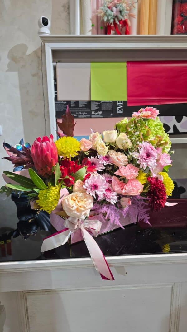 Aranjament floral colorat în cutie roz, cu hortensie, trandafiri, crizanteme, gerbera și protea – livrare rapidă în Râmnicu Vâlcea