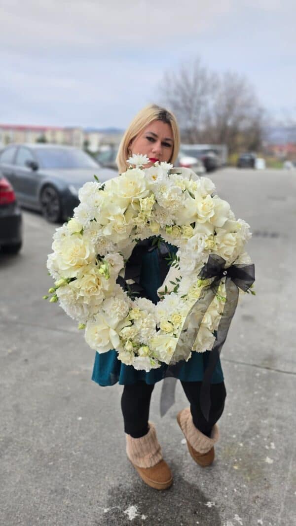 Coroană funerară albă cu flori naturale premium, dispuse într-o formă rotundă armonioasă.