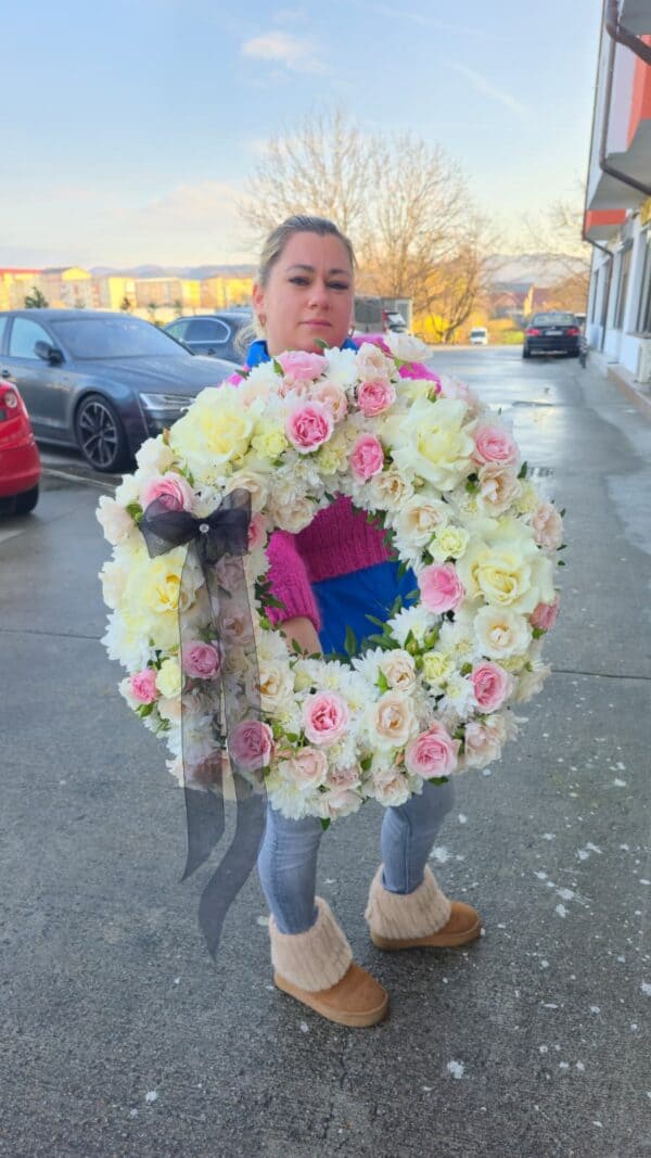 Coroană funerară alb roz, realizată din trandafiri și crizanteme naturale, așezată într-un design rotund elegant cu panglică neagră.