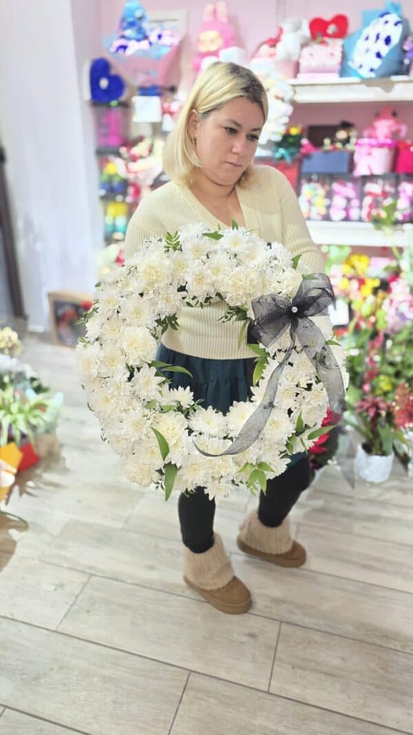 aranjament funerar rotund din crizanteme albe, decorat cu fundă neagră