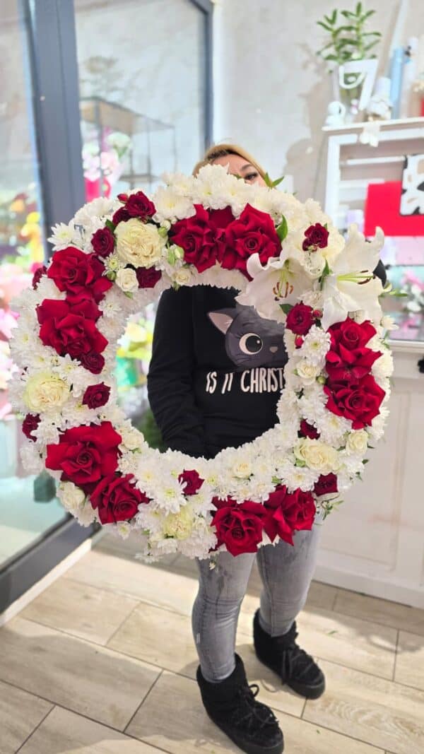 coroană funerară rotundă cu trandafiri roșii și albi și crini