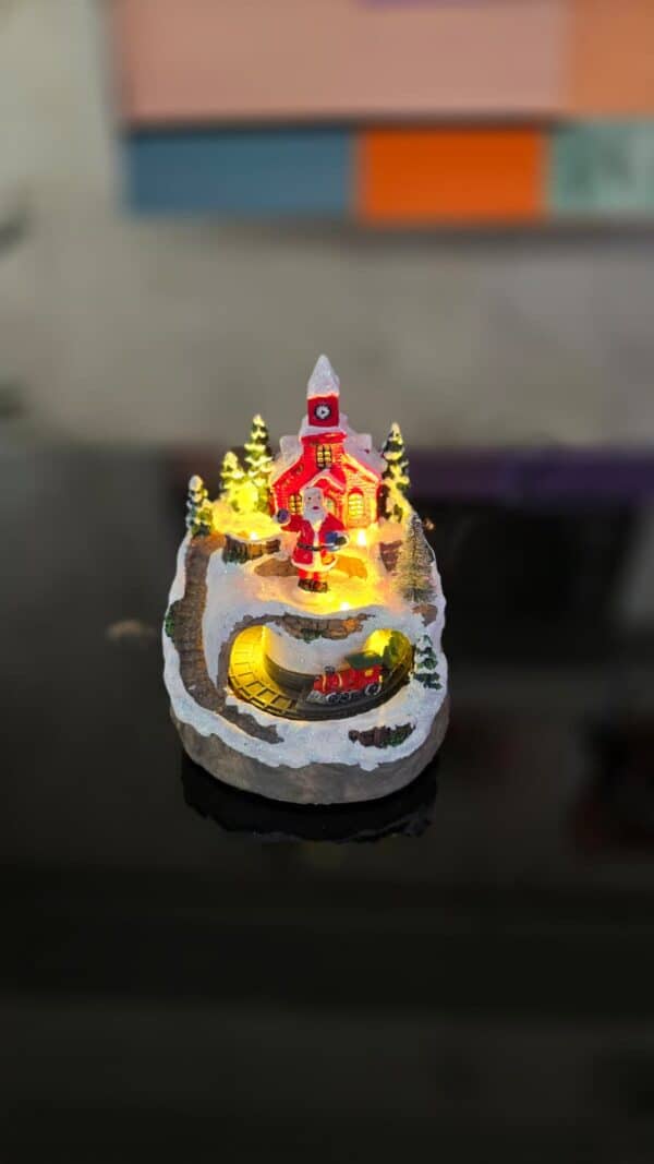 decorațiune crăciun cu moș crăciun, biserică roșie luminată și trenuleț rotativ
